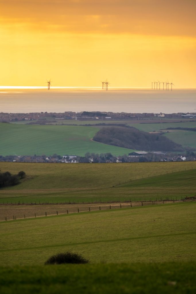 a view of a field with wind mills in the distance